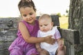 Happy adorable chubby baby girl sitting on a bench with her daughter sister