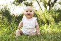 Happy adorable chubby baby girl sitting on the grass