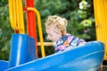 Happy adorable girl on children's slide on playground near kindergarten Montessori Royalty Free Stock Photo