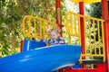 Happy adorable girl on children's slide on playground near kindergarten Montessori Royalty Free Stock Photo