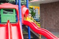 Happy adorable girl on children`s slide on playground near kindergarten Montessori on summer day Royalty Free Stock Photo