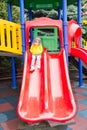 Happy adorable girl on children`s slide on playground near kindergarten Montessori on summer day Royalty Free Stock Photo