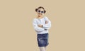 Happy pretty girl in trendy casual outfit and sunglasses posing on beige background Royalty Free Stock Photo