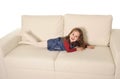 Happy adorable little girl with long hair lying on couch playful Royalty Free Stock Photo