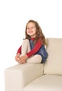 Happy adorable little girl with long hair sitting on the arm of couch Royalty Free Stock Photo