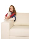 Happy adorable little girl with long hair sitting on the arm of couch Royalty Free Stock Photo