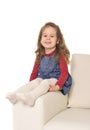 Happy adorable little girl with long hair sitting on the arm of couch Royalty Free Stock Photo