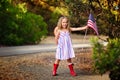 Happy adorable little girl smiling and waving American flag outs