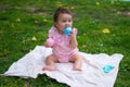 happy and adorable 7 or 8 months old baby girl playing with ball toy cheerful sitting on towel lying on grass city park in Royalty Free Stock Photo