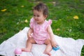 happy and adorable 7 or 8 months old baby girl playing with ball toy cheerful sitting on towel lying on grass city park in Royalty Free Stock Photo