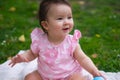 happy and adorable 7 or 8 months old baby girl playing with ball toy cheerful sitting on towel lying on grass city park in Royalty Free Stock Photo