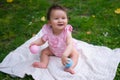 happy and adorable 7 or 8 months old baby girl playing with ball toy cheerful sitting on towel lying on grass city park in Royalty Free Stock Photo