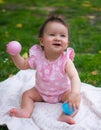 happy and adorable 7 or 8 months old baby girl playing with ball toy cheerful sitting on towel lying on grass city park in Royalty Free Stock Photo