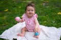 happy and adorable 7 or 8 months old baby girl playing with ball toy cheerful sitting on towel lying on grass city park in Royalty Free Stock Photo