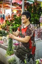 Happy adult asian chinese woman sells beautiful flowers at the market