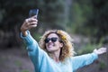 Happy adult caucasian woman enjoying the phone to take picture to share on social media - outdoor leisure activiy people and green Royalty Free Stock Photo