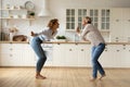 Adult daughter and mother dancing at modern kitchen celebrate renovation