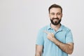 Happy adult european man smiling cheerfully while pointing left with index finger, over gray background. Guy in theme Royalty Free Stock Photo