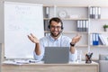 Happy adult european man teacher in glasses, headphones spreads arms to sides and looks at laptop Royalty Free Stock Photo