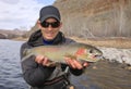 Happy adult fisherman holding steelhead trout