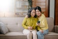 Happy adult granddaughter and senior grandmother having fun enjoying talk sit on sofa in living room at home Royalty Free Stock Photo