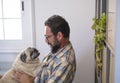 Happy adult hipster man hug and play with his old best friend dog pug at home - people and lovely animals life indoor Royalty Free Stock Photo