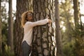 Happy adult lady hug tree trunk in outdoor leisure park activity. Concept of environment and ambient nature care. People love Royalty Free Stock Photo