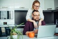 Happy adult loving family couple looking at laptop screen, sitting at table in kitchen. Bearded man showing funny video on Royalty Free Stock Photo