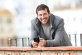 Happy adult man holding phone looks at camera in winter