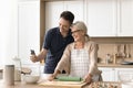 Happy adult man and senior blonde mom baking in kitchen Royalty Free Stock Photo