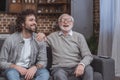 happy adult son and senior father laughing on sofa Royalty Free Stock Photo