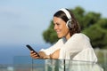 Happy adult woman with headphones listens music on a balcony Royalty Free Stock Photo