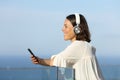 Happy adult woman with headphones listens music on the beach Royalty Free Stock Photo