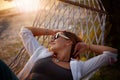 Happy adult woman in sunglasses enjoying summer and vacation in hammock, relaxing mental healh