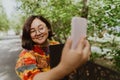 Happy adult woman taking a selfie with her mobile phone in blooming park. Royalty Free Stock Photo