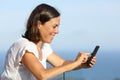 Happy adult woman uses phone on the beach Royalty Free Stock Photo