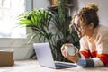 Happy adult woman using laptop at home and drinking coffee. Modern lady smiling at the computer screen in video chat connection Royalty Free Stock Photo