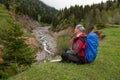 Happy adventurer with backpack sits in a mountain gorge