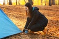 Happy adventurous girl setting camp in autumn forest