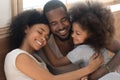 Happy affectionate african american family of three bonding embracing