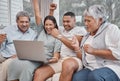 Happy and affectionate mixed race family of four using a laptop to watch sports and cheer on their favourite team in the Royalty Free Stock Photo