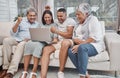 Happy and affectionate mixed race family of four using a laptop to watch sports and cheer on their favourite team in the Royalty Free Stock Photo