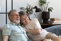 Happy affectionate 60s couple resting on sofa.