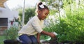 Happy african amercian girl gardening, watering plants in garden