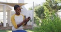 Happy african amercian woman gardening, taking picture of plants in garden