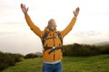 Happy african american backpacker standing outdoors with hands raised