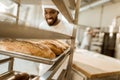 happy african american baker looking at fresh loaves of bread Royalty Free Stock Photo