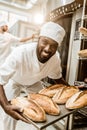 happy african american baker taking bread loaves from oven Royalty Free Stock Photo