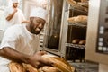 happy african american baker with tray of fresh loaves of bread