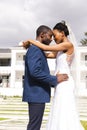 Happy african american bride and groom embracing in front of house in sunny garden Royalty Free Stock Photo